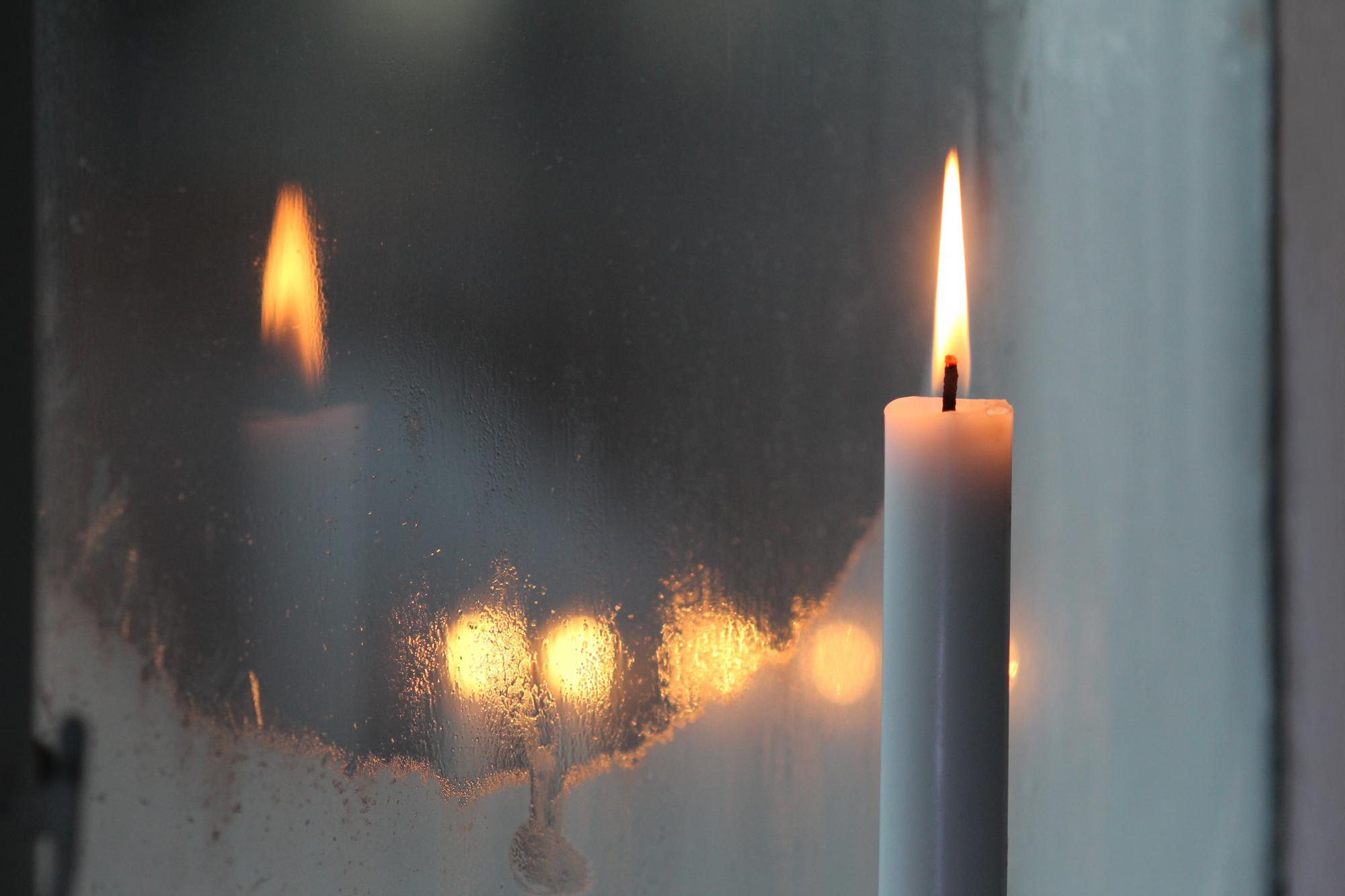 lit candle in front of frosted window