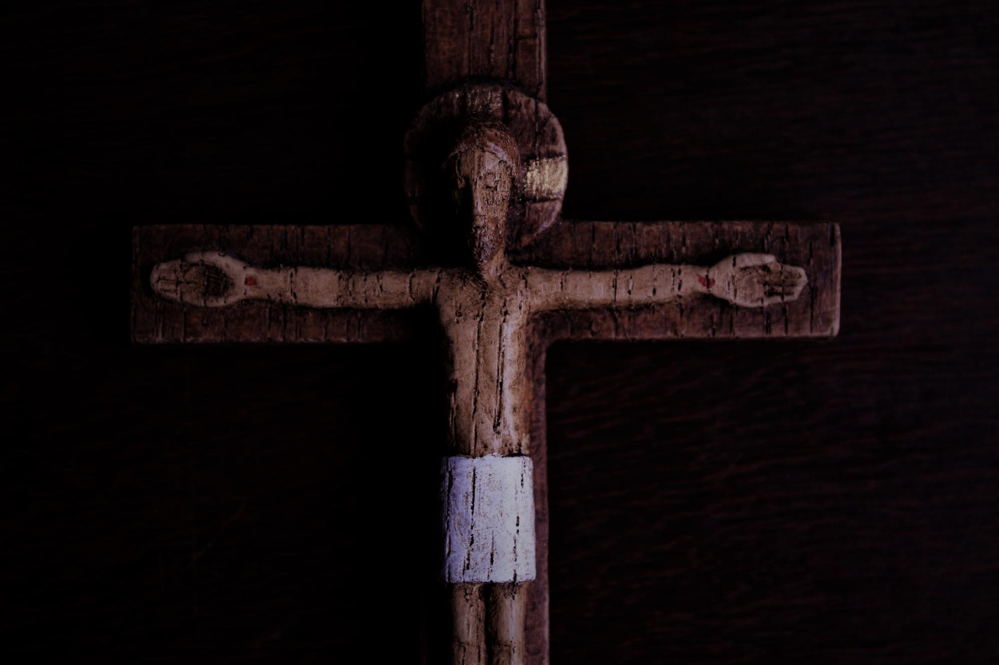 Dark photo of worn, wooden crucifix 