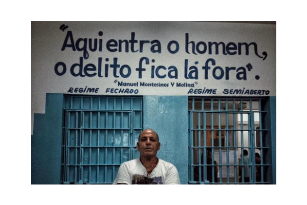 Man stands in front of doorway that reads in Spanish "the man enters, the crime stays outside."
