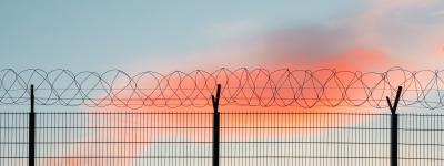 Barbed wire fence in front of blue and pink sky