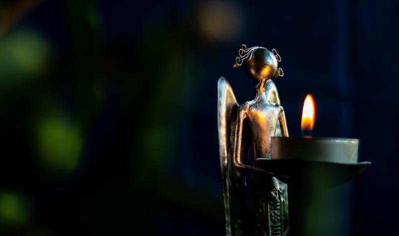 metal statue of an angel holding a candle with a lit flame