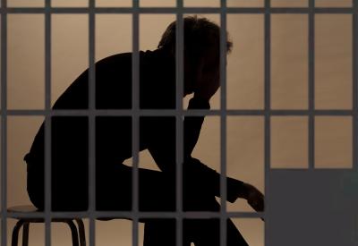 man thinking in prison cell
