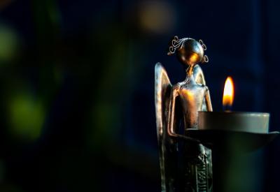 metal statue of an angel holding a candle with a lit flame
