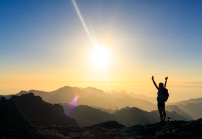 person with arms raised at mountain summit