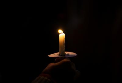burning candle in front of a black background