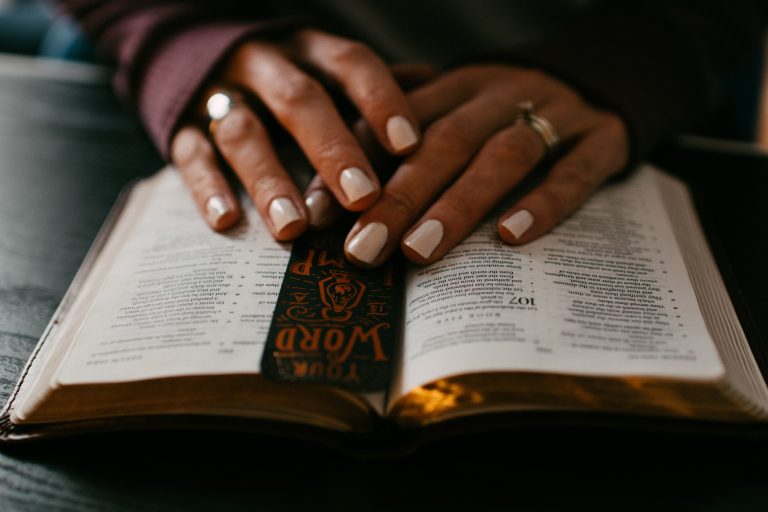 Folded hands on top of a Bible