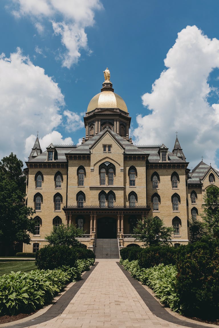 Iconic Main Building with the Golden Dome at University of Notre Dame, Indiana, set against a sunny sky.